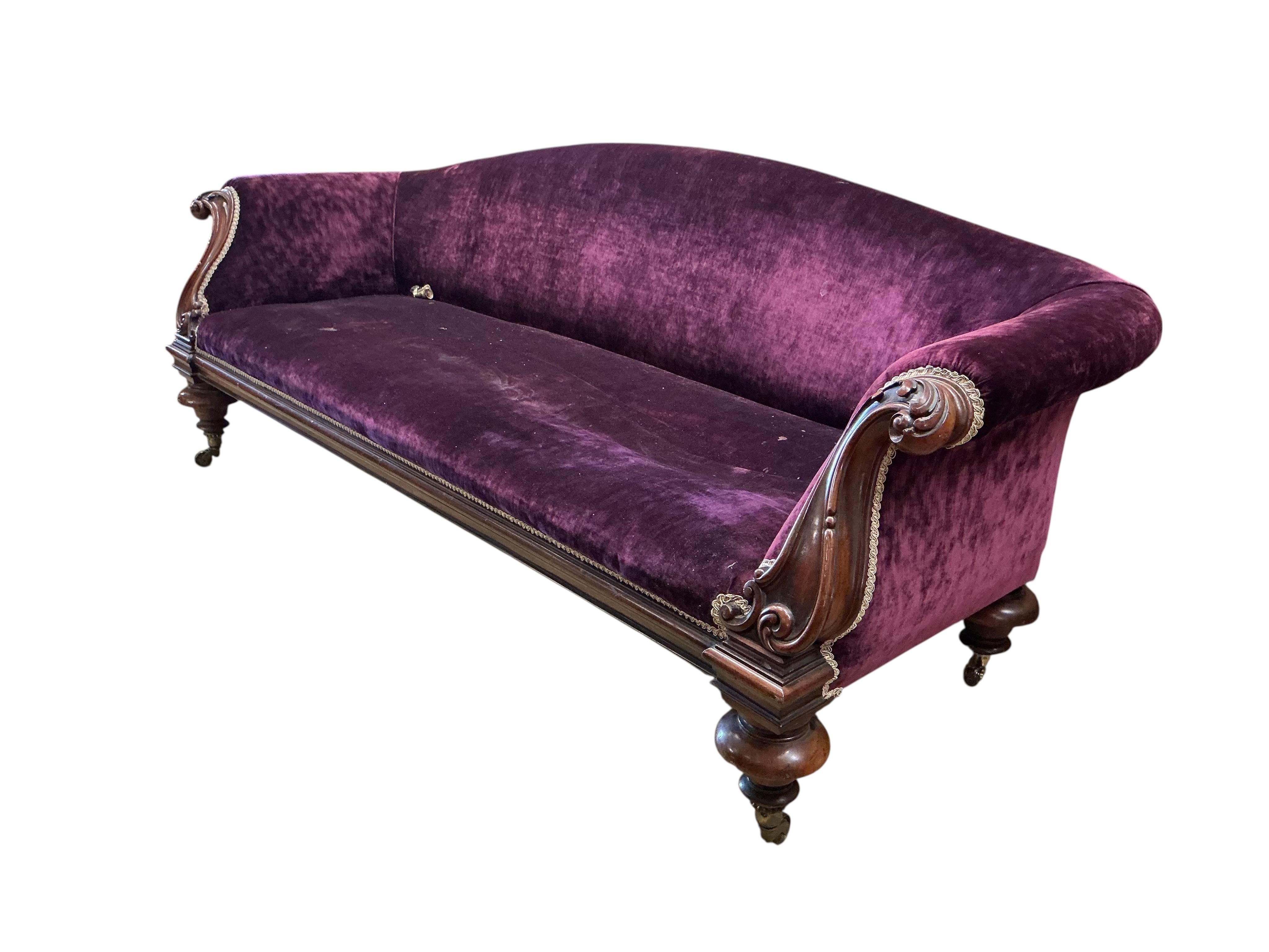 A Victorian mahogany settee upholstered in purple velvet, one rear castor detached, width 230cm, depth 84cm, height 74cm.